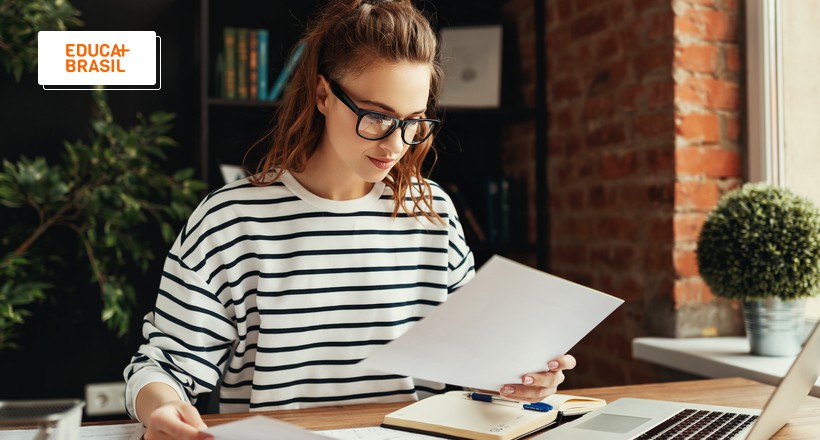 Estudante conferindo no papel documentos para comprovação de dados Prouni.