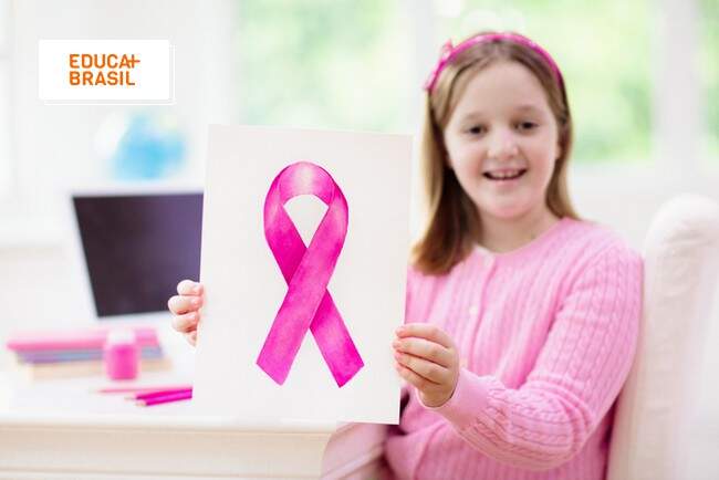 Menina segurando cartaz com laço rosa em alusão ao Outubro Rosa nas escolas. Menina segurando cartaz com laço rosa em alusão ao Outubro Rosa nas escolas.
