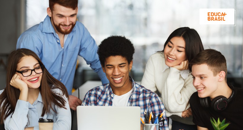 Estudantes estagiários reunidos e olhando o notebook.
