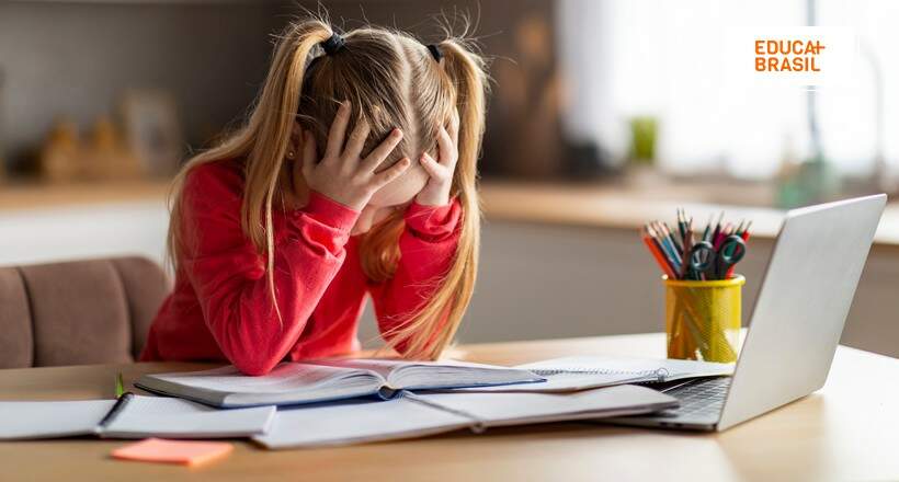 Criança com a mão na cabeça, triste e precisando de reforço escolar.