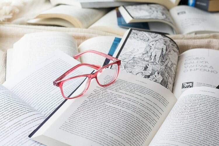 óculos rosa em cima de livros abertos