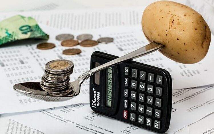 Calculadora servindo de equilíbrio para uma colher com moedas Calculadora servindo de equilíbrio para uma colher com moedas