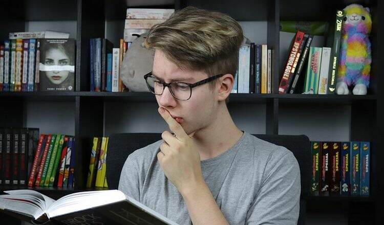 Menino com livro em mãos estudando Menino com livro em mãos estudando
