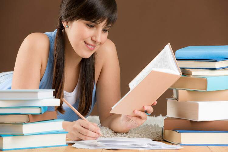 Garota diante de livros e fazendo anotações. Garota diante de livros e fazendo anotações.