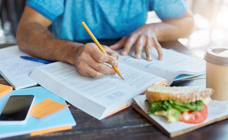 Estudante lendo o conteúdo de um livro Estudante lendo o conteúdo de um livro