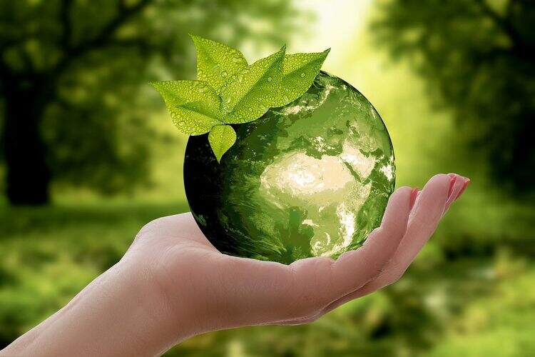Uma mão segura o planeta na cor verde. Uma mão segura o planeta na cor verde.