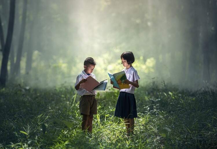 Duas crianças com livros abertos no meio de uma floresta Duas crianças com livros abertos no meio de uma floresta