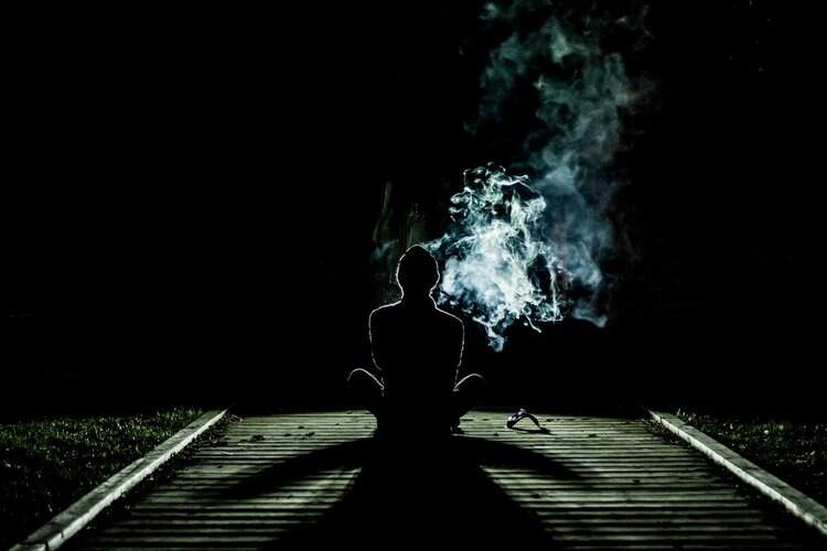 Pessoa sentada no escuro fumando Pessoa sentada no escuro fumando