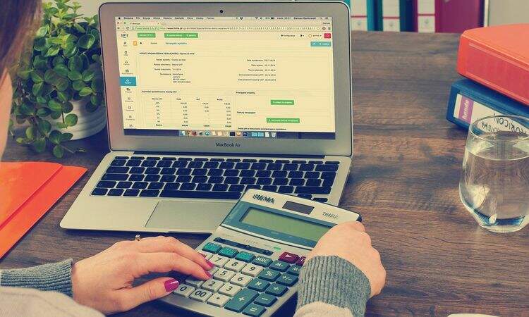 Mulher usando calculadora para fazer planilhas Mulher usando calculadora para fazer planilhas