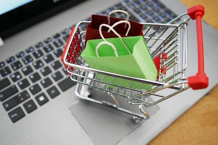 Pequeno carrinho de compras em cima de um notebook Pequeno carrinho de compras em cima de um notebook
