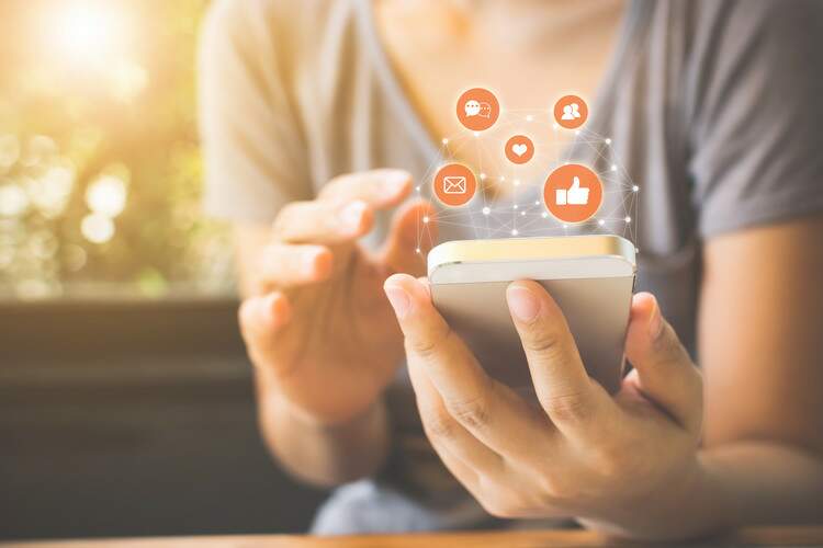 Uma pessoa com celular na mão e conectada a várias redes sociais. Uma pessoa com celular na mão e conectada a várias redes sociais.