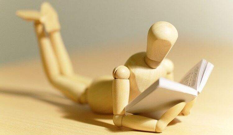 Boneco de madeira com livro em mãos Boneco de madeira com livro em mãos