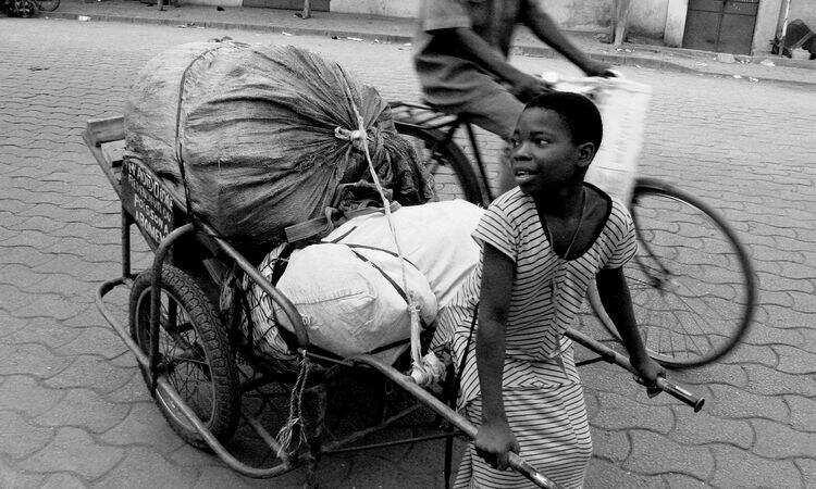 Menina carregando carrinho com materiais recicláveis Menina carregando carrinho com materiais recicláveis