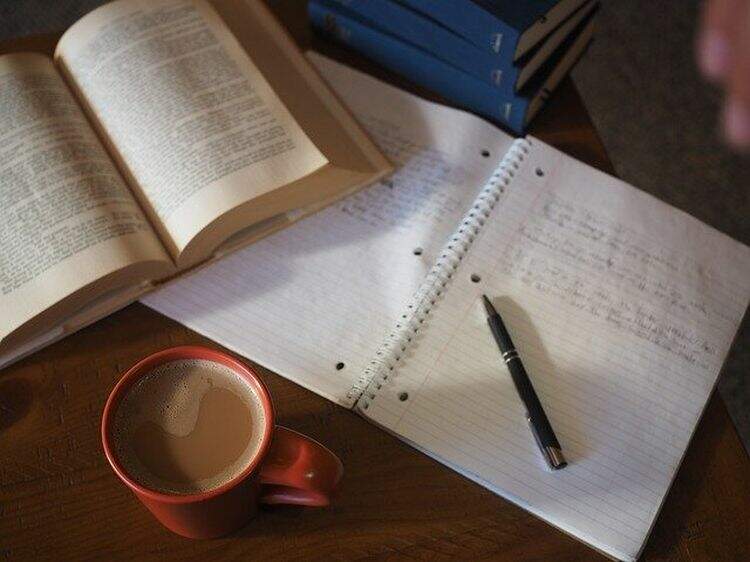 livro ao lado de um caderno com anotações livro ao lado de um caderno com anotações