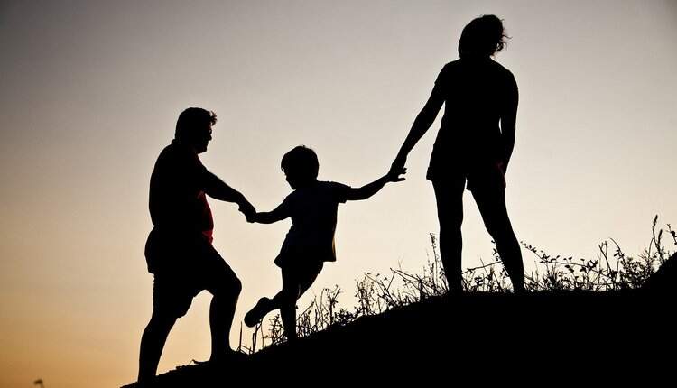 Pai e mãe segurando as mãos do seu filho